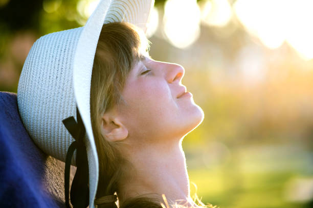 istock Young woman relaxing outdoors on sunny summer day. Happy lady in straw hat daydreaming thinking. Calm beautiful smiling girl enjoying fresh air relax with closed eyes. 1216791103