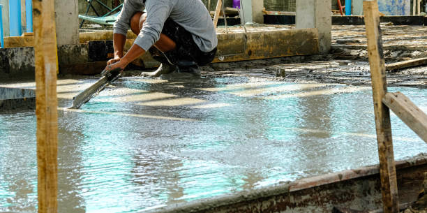 istock worker man working wet cement floor by use trowel hands spreading poured concrete for strong after dry. 1216793940