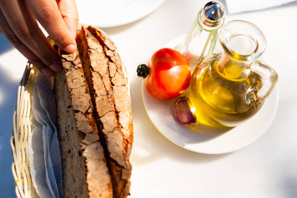 top view of classic catalan dish called "pan con tomate" with garlic, olive oil, tomatoes, bread with woman hand picking bread slice stock photo