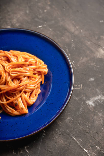 Traditional pasta with tomato sauce in blue plate on the rustic background Traditional pasta with tomato sauce in blue plate on the rustic background. Selective focus. cooked selective focus vertical pasta stock pictures, royalty-free photos & images