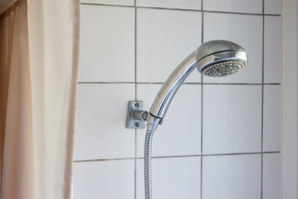 istock Dirty corroded limescale calcified shower head hanging from a stand inside cabin visible curtain 1216799192
