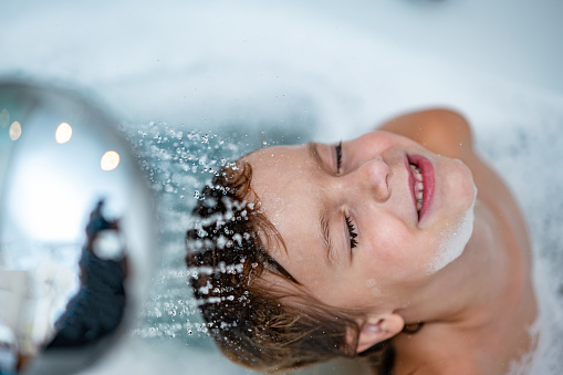 Cute little boy is washing head in bathtub