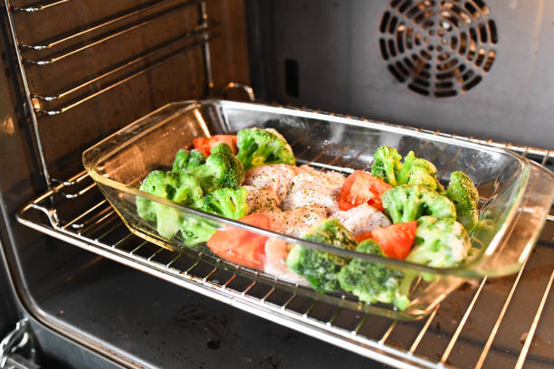 istock raw turkey with vegetables on a baking sheet. cauliflower spomidora. Dish with raw turkey spice on a glass baking pan, top view 1216802025