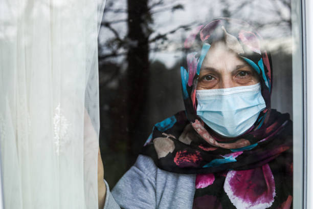 istock oman in Quarantine Looking Out The Window 1216804320