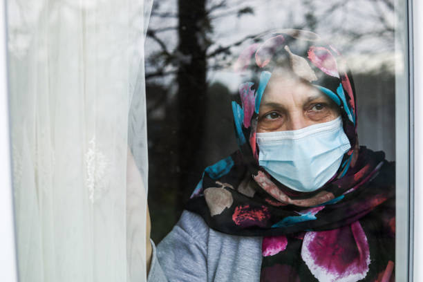 istock oman in Quarantine Looking Out The Window 1216804667