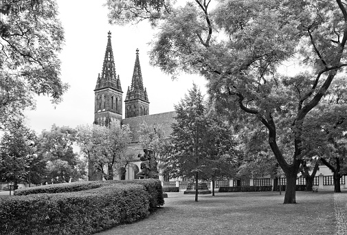 Prague, Czech Republic - September 17, 2016: Black and white cityscape with Basilica of St Peter and St Paul, which is a neo-Gothic church in Vysehrad fortress, seen across park