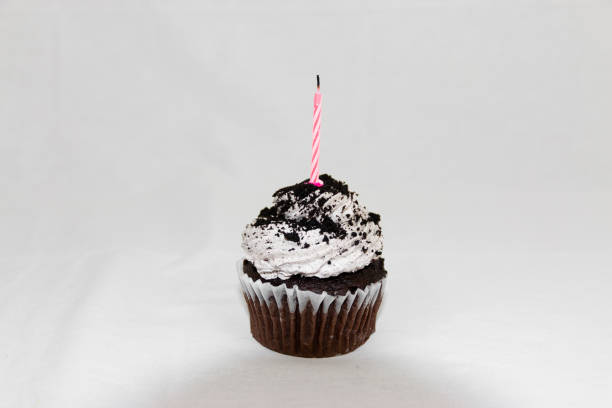 istock Cookies and cream cupcake with pink candle and white background 1216805416