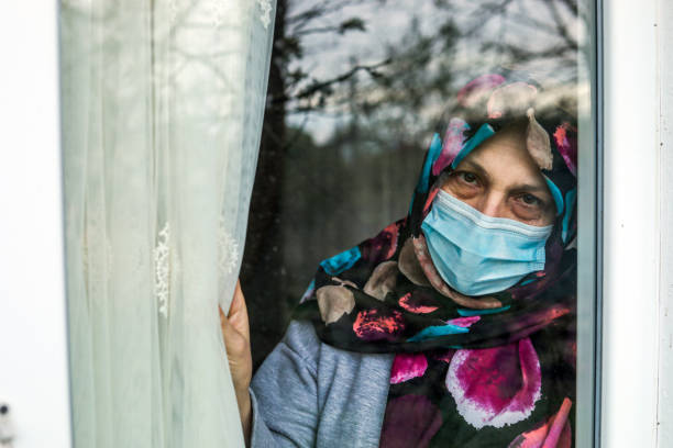 istock oman in Quarantine Looking Out The Window 1216805572