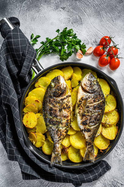 istock Grilled Dorado fish with potatoes in a pan. Gray background. top view 1216808094