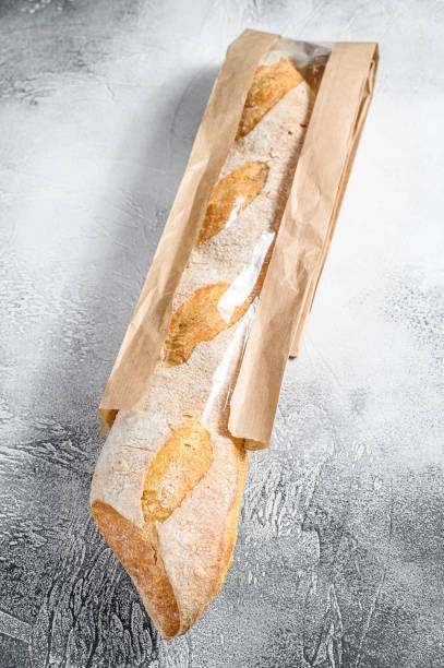 istock Fresh baguette in a paper craft bag. gray background. top view 1216808236
