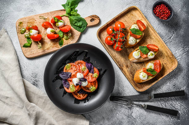 istock Assorted Caprese salad, skewers, canapes, bruschettes with cherry tomatoes, mozzarella and Basil. gray background. top view 1216810166
