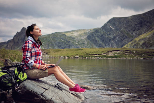 istock Hiker woman is relaxing and using laptop in the mountain 1216810228