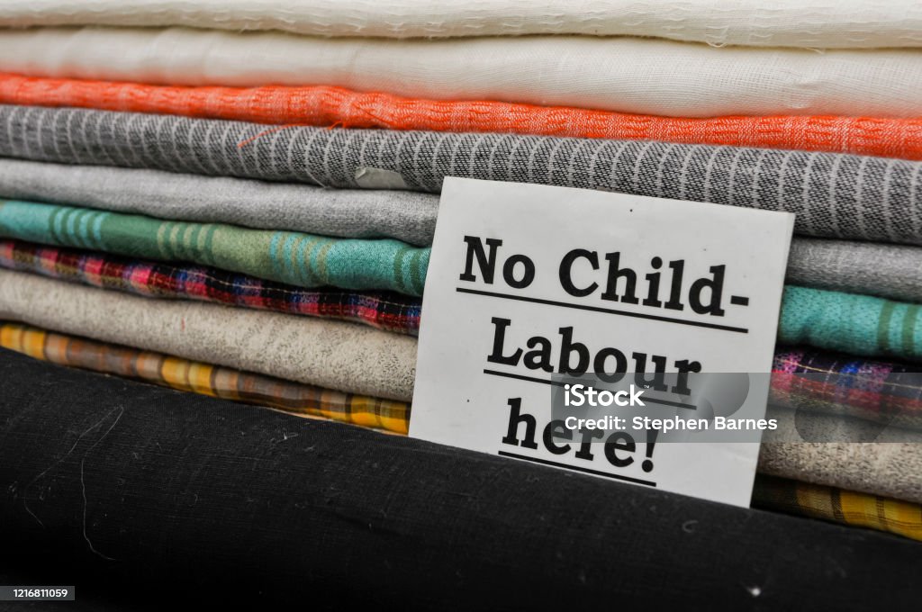 Firme en una tienda de telas aconsejando a los clientes que no se utiliza trabajo infantil en la producción de sus productos. - Foto de stock de Trabajo de menores libre de derechos