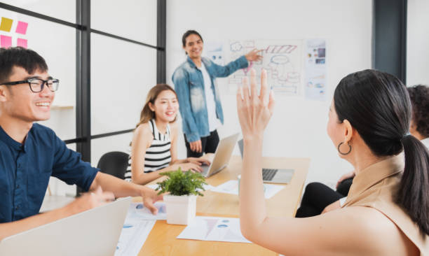 Asian business people rising hand for asking question while meeting in office