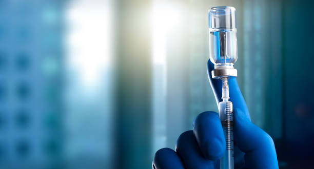 A medical hand in a glove holds an ampoule with a vaccine and a syringe with illustration The hands in blue glove of the scientist hold the processor syringe photos stock pictures, royalty-free photos & images