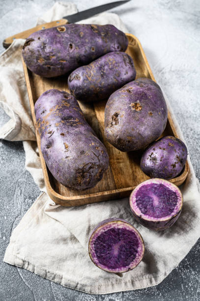 istock Raw purple potatoes on a chopping Board. Gray background. Top view 1216812483
