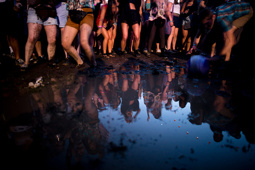 Crowd of teenagers dancing around mud puddle at a music festival in New York City