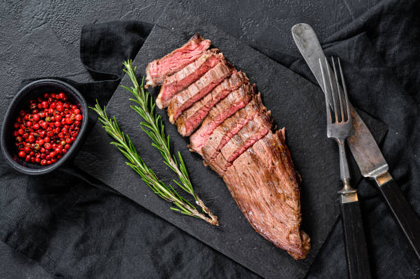 istock Roasted medium rare sliced flank beef steak. Black background. Top view 1216813996
