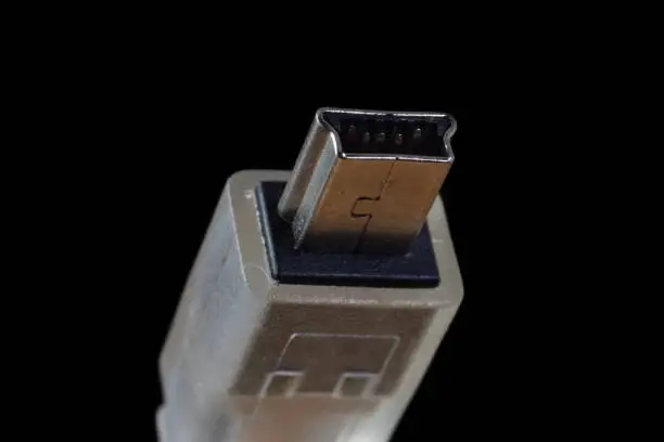 USB mini B plug isolated on a black background. Common 5 pin digital cammera data connector.
