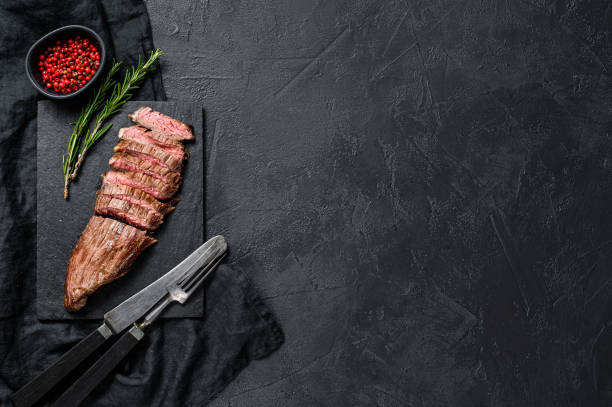 istock Sliced beef flank steak medium rare. Black background. Top view. Space for text 1216816056