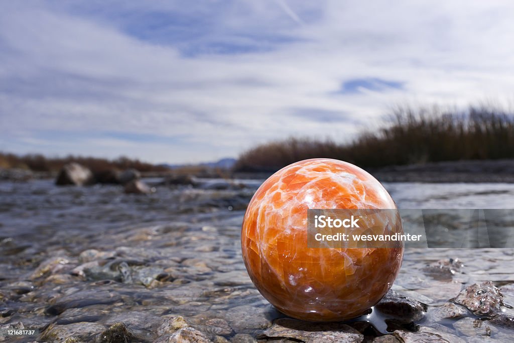 Orange Jasper Sphere at Riverbank  Blue Stock Photo
