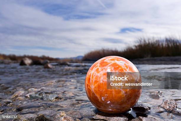 Orange Jasper Sphere At Riverbank Stock Photo - Download Image Now - Blue, Circle, Cloud - Sky