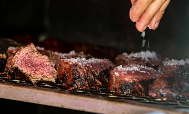 grill do grillowania, solenie mięsa z grubą solą i zabranie go na grill do pieczenia - broiling zdjęcia i obrazy z banku zdjęć