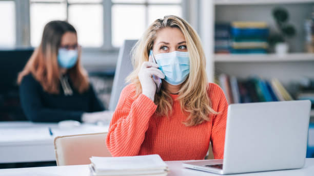 Colleagues in the office working while wearing medical face mask during COVID-19 Colleagues in the office working while wearing medical face mask during COVID-19 world health organization photos stock pictures, royalty-free photos & images