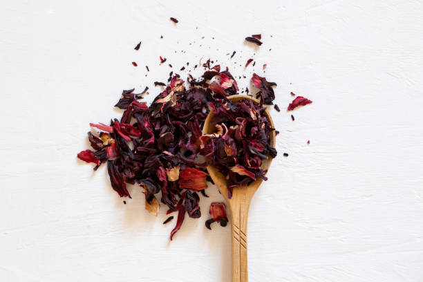 dry tea leaves of red hibiscus in a wooden spoon. - dry tea imagens e fotografias de stock