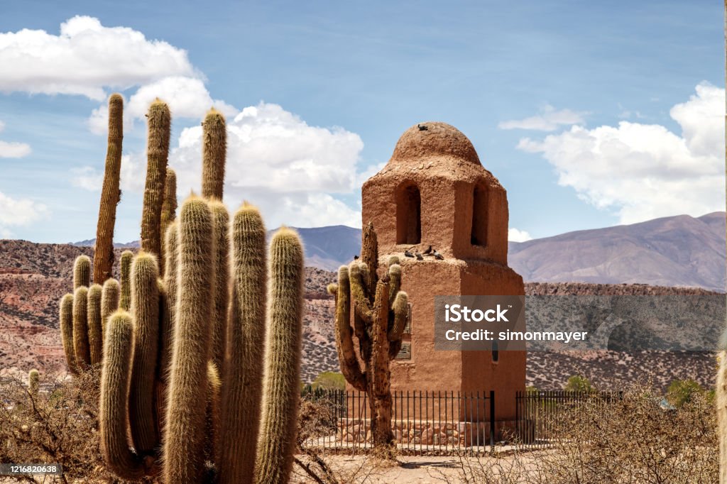 Adobe bell tower with birds next to several cactus in Humahuaca, Jujuy, Argentina Humahuaca Stock Photo