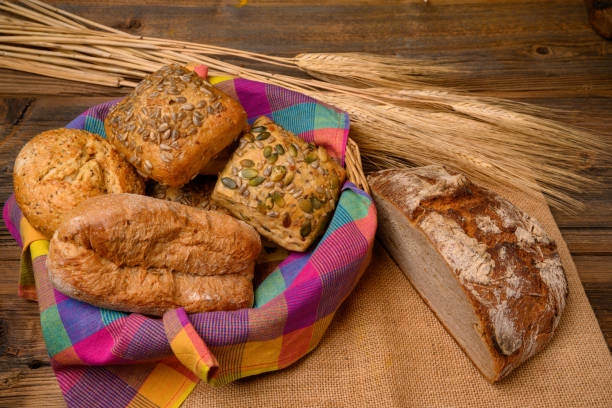 istock Freshly various buns in a basket and a half whole grain bread on a jute fabric placed on a rustic wooden background with grain ears. 1216821016