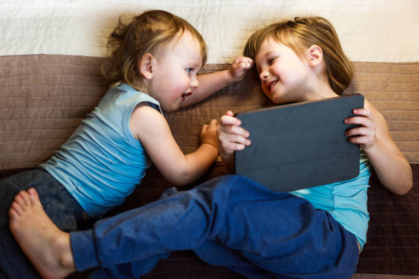 istock two siblings laying on the bed with tablet 1216822473