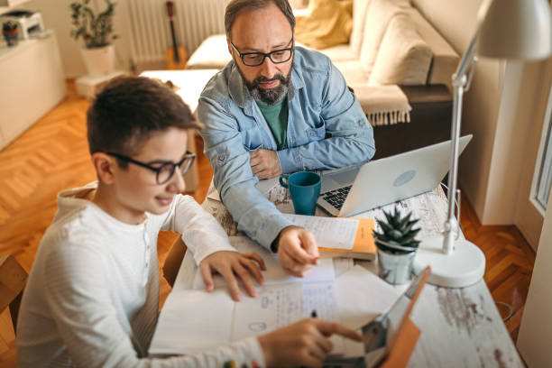 istock Father helping son with homework at home office 1216824391