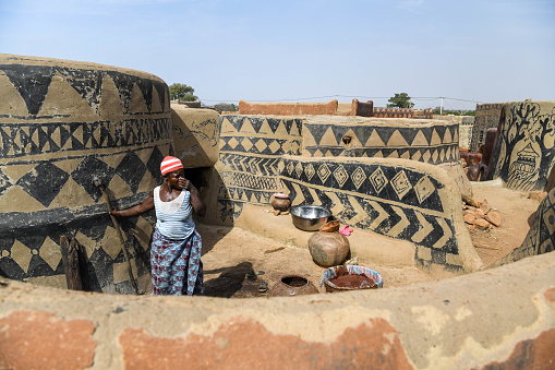 Africa, Burkina Faso, Pô region, Tiebele. Cityscape view of the royal court village in Tiebele. A woman is cooking