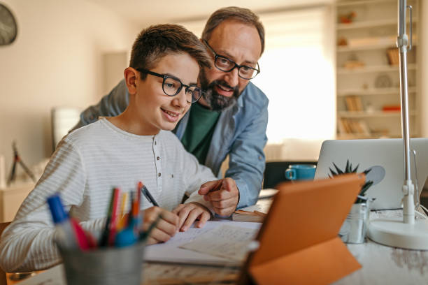 père heureux aidant le fils avec des devoirs - parent teenager caucasian teenage boys photos et images de collection