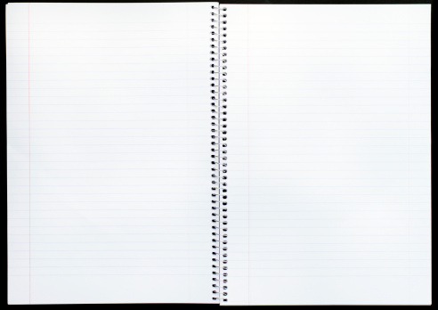 An open spiral bound notebook with a plastic ball point pen lies open on a wood grained desk top.