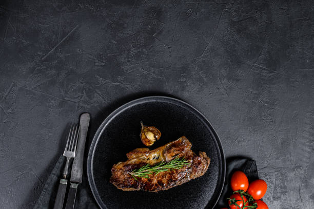 istock Beef strip loin steak on black background. Space for text. Marble beef. 1216827762