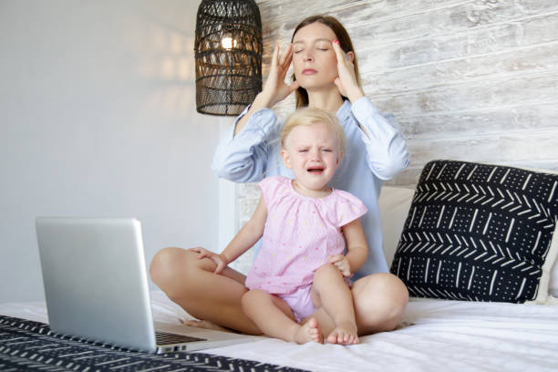 istock Work from home with a little one. Young mother trying to work on laptop while babysitting. Stressful mum trying to multitask. 1216830537