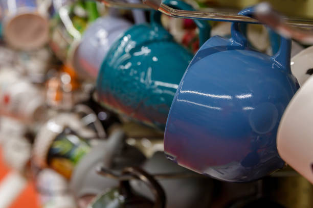 ceramic colored mugs hang on hooks on a window in a glassware store