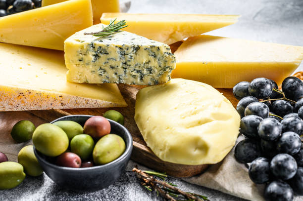 istock Different pieces of cheese with nuts olives and grapes. Assorted delicious snacks. Gray background. Top view 1216831402
