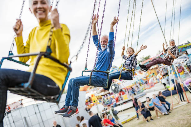 istock Happy senior friends having fun while riding on chain swing at amusement park. 1216831991