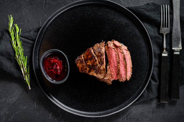 istock Sliced grilled marbled beef steak. Beef tenderloin. Black background. Top view 1216832084