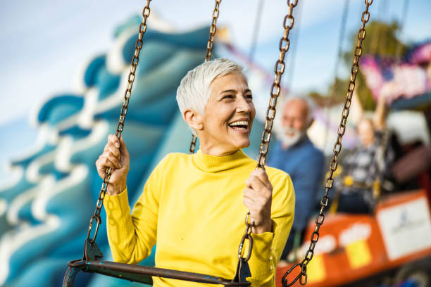 istock Happy senior woman having fun while riding on chain swing at amusement park. 1216832393