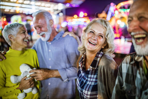 istock Happy mature couples enjoying at amusement park by night. 1216832422