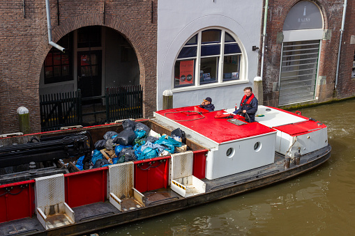 Utrecht, the Netherlands - 16 Mar, 2020: Port service boat through the Oudegracht canal in the historical city of Utrecht picking up waste