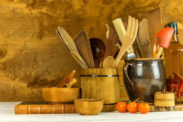 Utilities chef. Wooden kitchen utensils with glass bottle of olive oil on wooden planks background. Home cooking.
