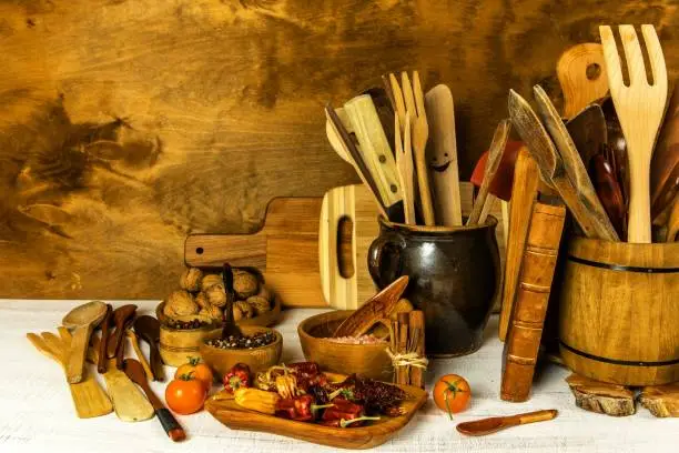 Utilities chef. Wooden kitchen utensils with glass bottle of olive oil on wooden planks background. Home cooking.
