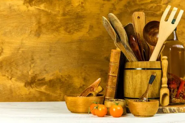 Utilities chef. Wooden kitchen utensils with glass bottle of olive oil on wooden planks background. Home cooking.