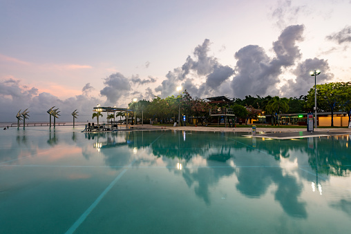 silouette landscape scenery of swimming pool with sunbed and coconut tree at beach front and seaside resort at Huahin Thailand during sunrising