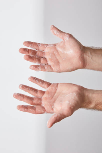 istock partial view of man showing hands with soap foam on grey background background 1216840928
